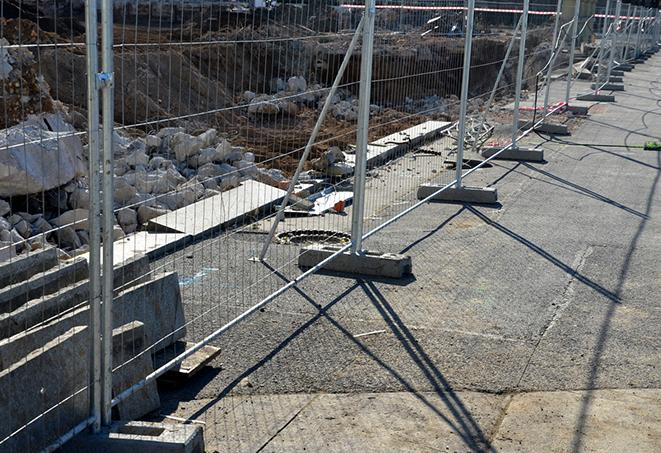 a row of temporary fence panels at a construction site, providing safety and security